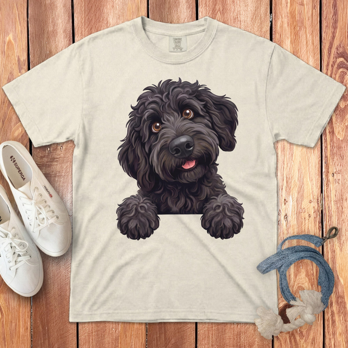 Illustration of a black poodle with its paws over the bottom of a beige t-shirt.