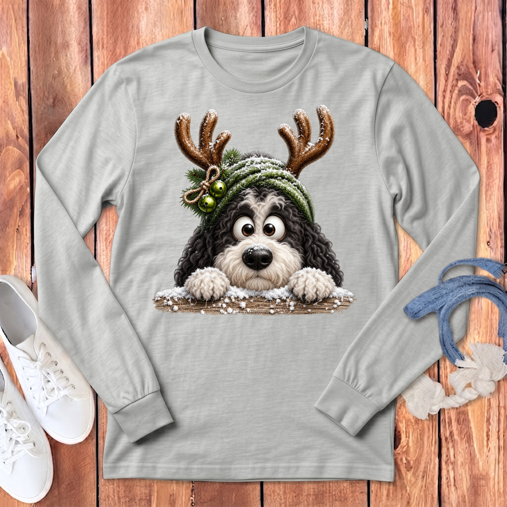Fluffy dog with antlers and snow-covered hat peeks over a wooden fence.