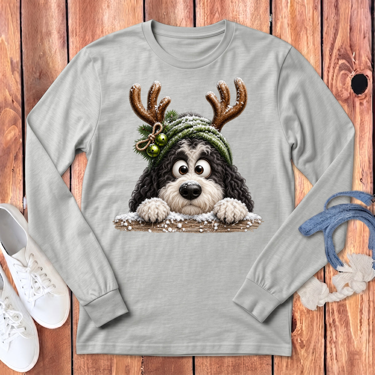 Fluffy dog with antlers and snow-covered hat peeks over a wooden fence.