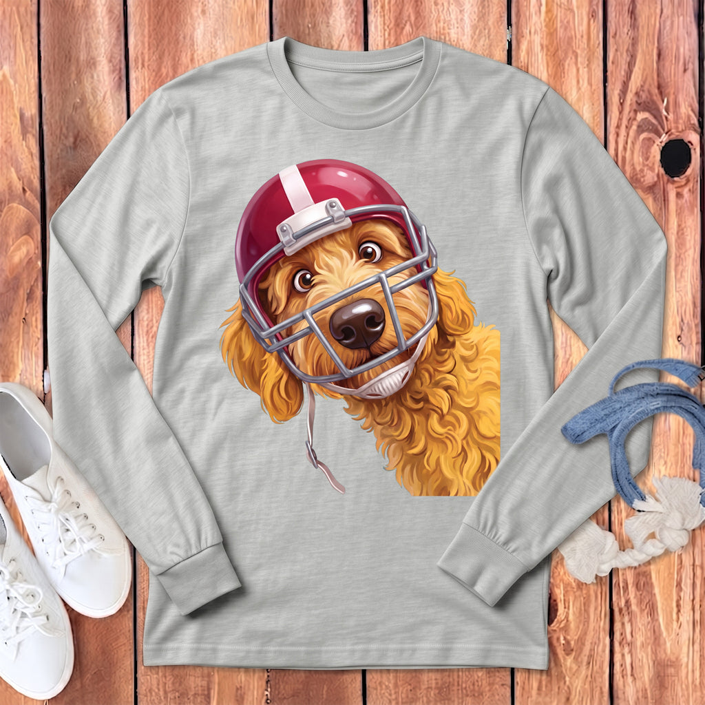 Goldendoodle dog wearing a red football helmet on a light gray long-sleeved shirt.