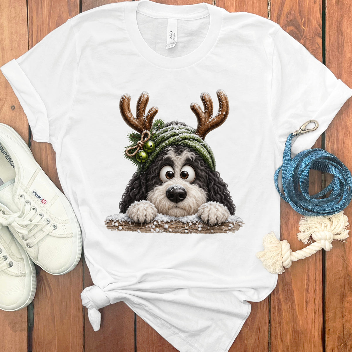 White t-shirt with a cartoon bernedoodle wearing antlers and a green beanie.
