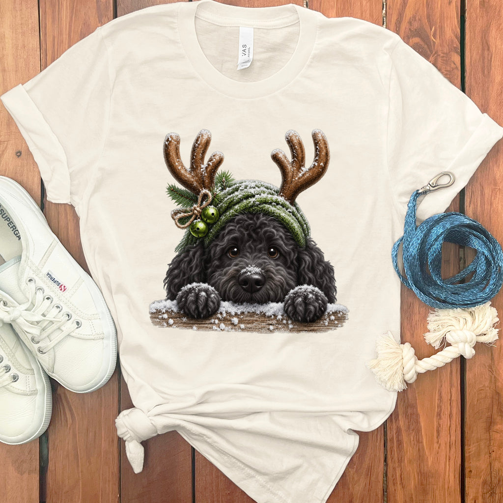 Cream t-shirt with illustration of black dog wearing reindeer antlers and green hat.