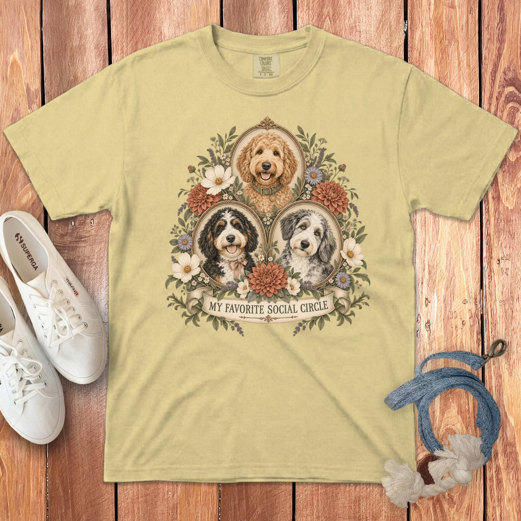 Yellow t-shirt featuring three framed dogs, floral illustrations, and text reading MY FAVORITE SOCIAL CIRCLE.
