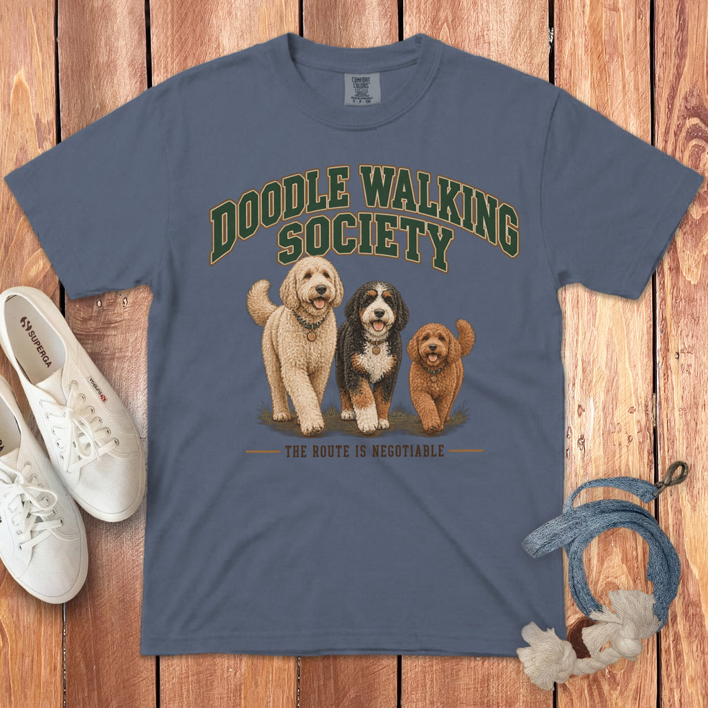 Blue crewneck t-shirt with Doodle Walking Society graphic, three doodle dogs, and text on wooden background.