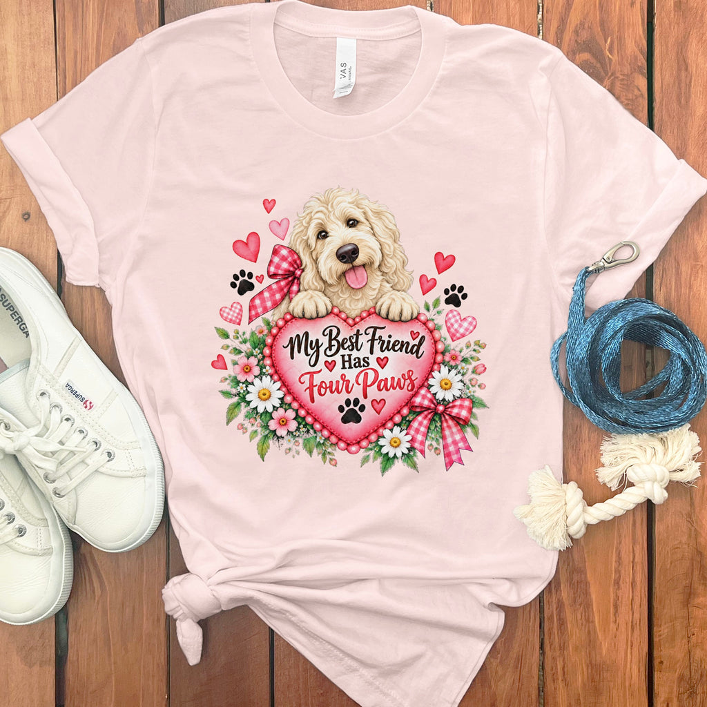 Light pink t-shirt featuring a Golden Doodle graphic, text reading My Best Friend Has Four Paws, white sneakers, and a blue leash on a wooden background.
