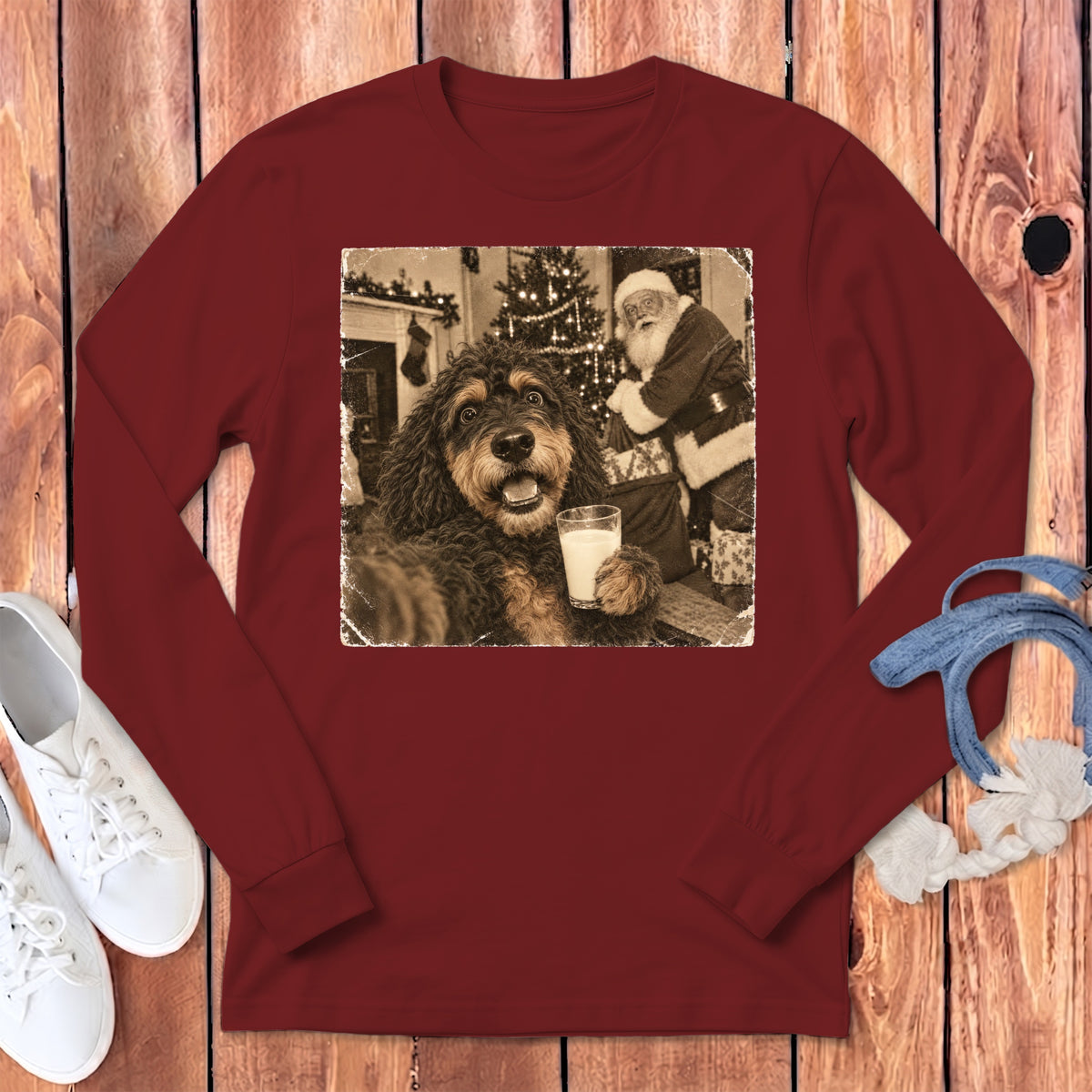Maroon long-sleeved t-shirt featuring a graphic of a dog holding a glass of milk with Santa Claus in the background.