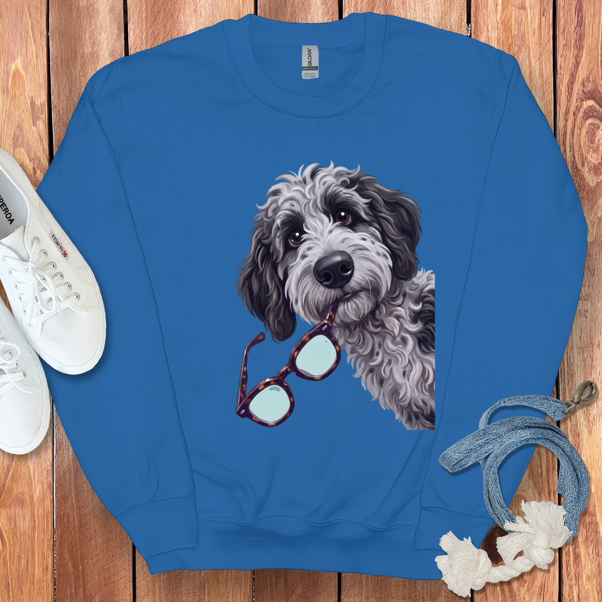 Blue crewneck sweatshirt featuring a graphic of a shaggy dog holding glasses in its mouth.