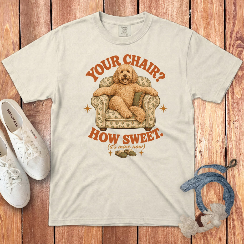 Off-white crewneck t-shirt featuring a graphic of a golden doodle relaxing in a floral armchair with text.