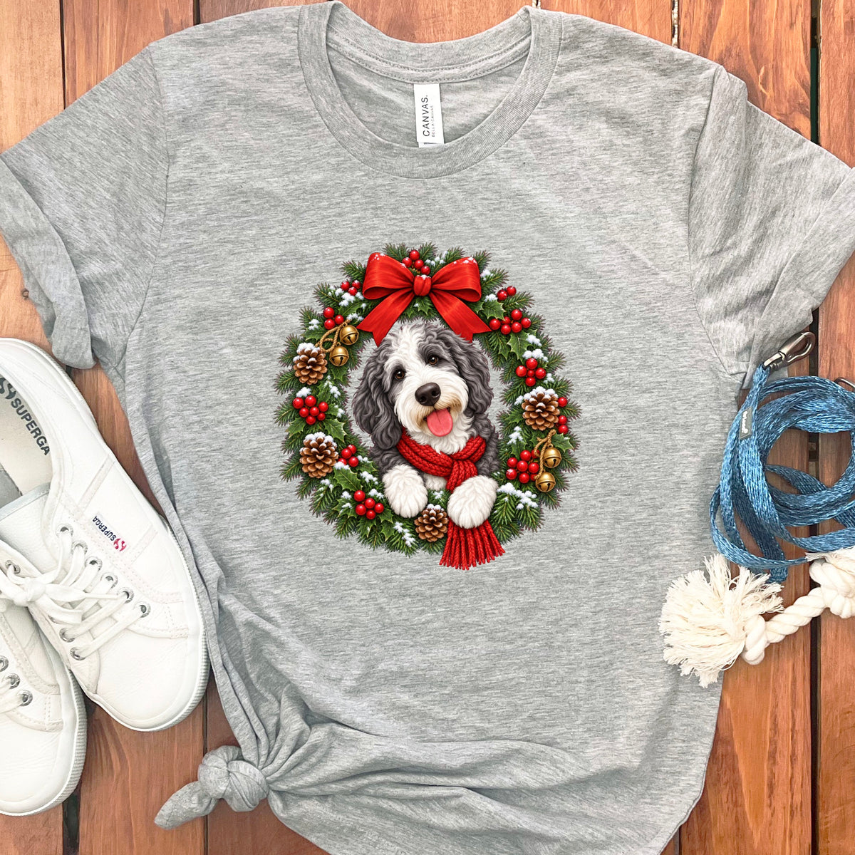 Gray t-shirt featuring a Christmas wreath graphic with a fluffy dog wearing a red scarf.