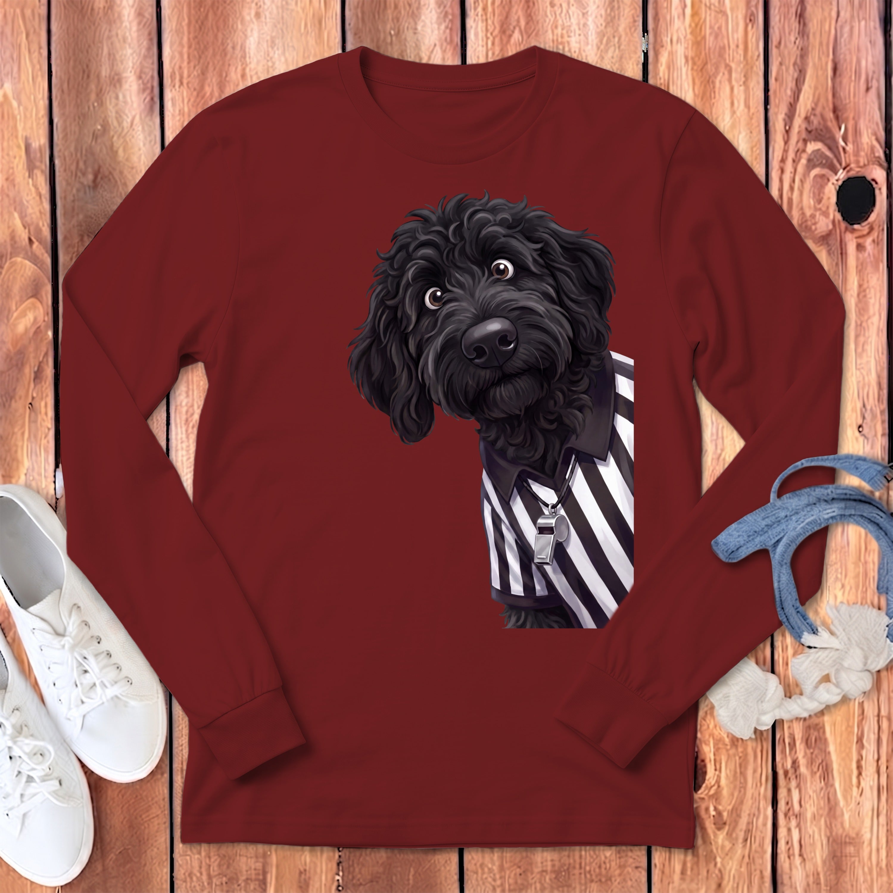 Black poodle wearing a referee shirt and whistle on a maroon long-sleeve shirt.