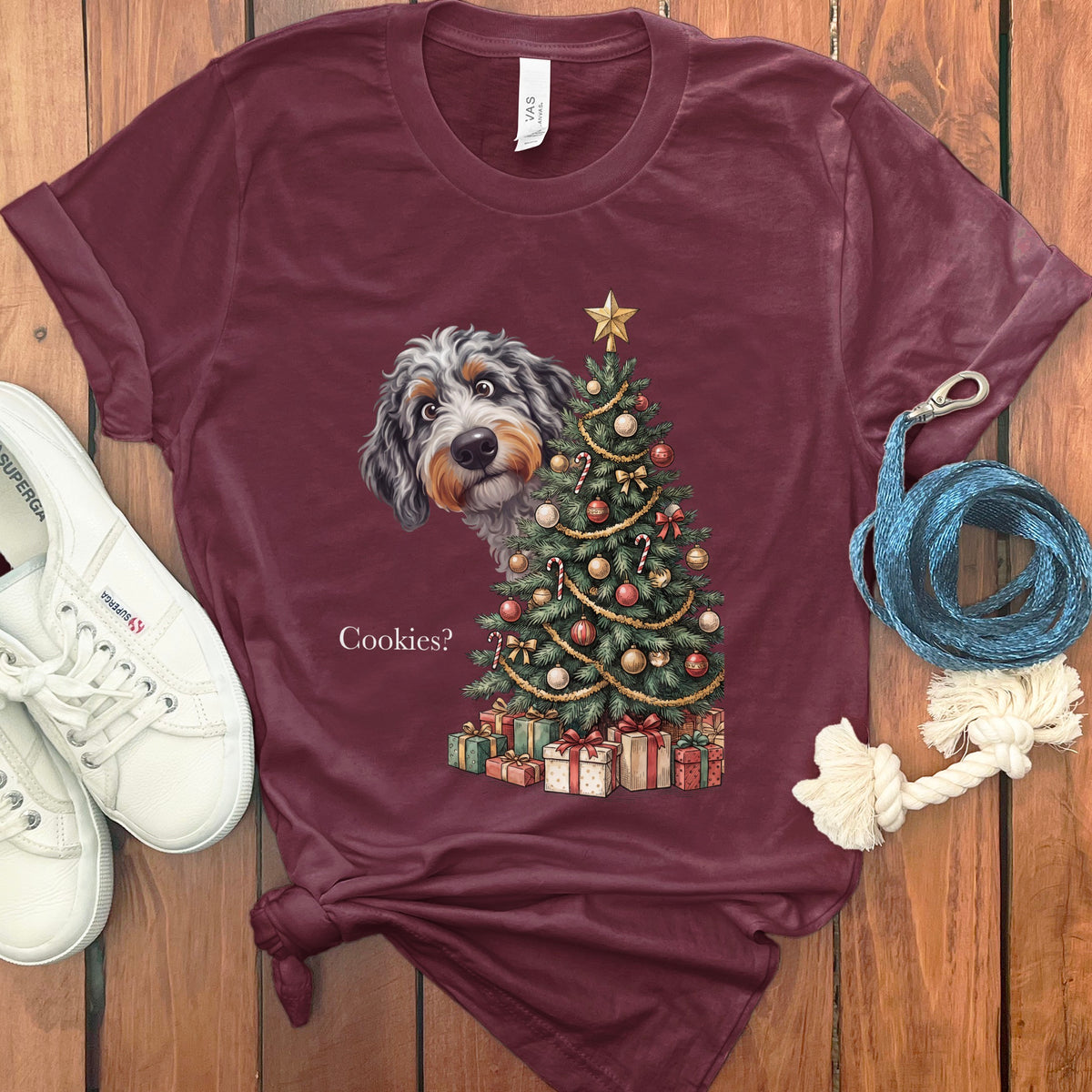 Maroon t-shirt with a dog peeking behind a Christmas tree and text "Cookies?"
