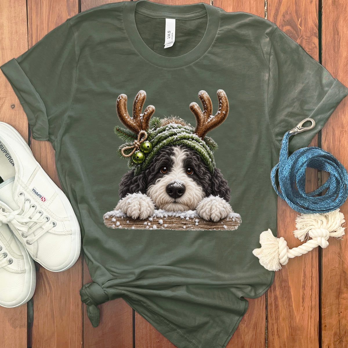 Green t-shirt featuring a dog wearing a festive hat and antlers.