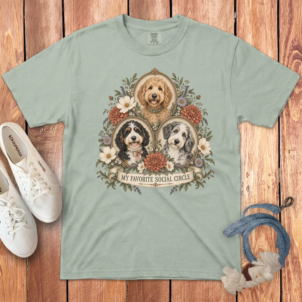 Sage green t-shirt featuring three doodle dogs in oval frames surrounded by flowers and the text MY FAVORITE SOCIAL CIRCLE.