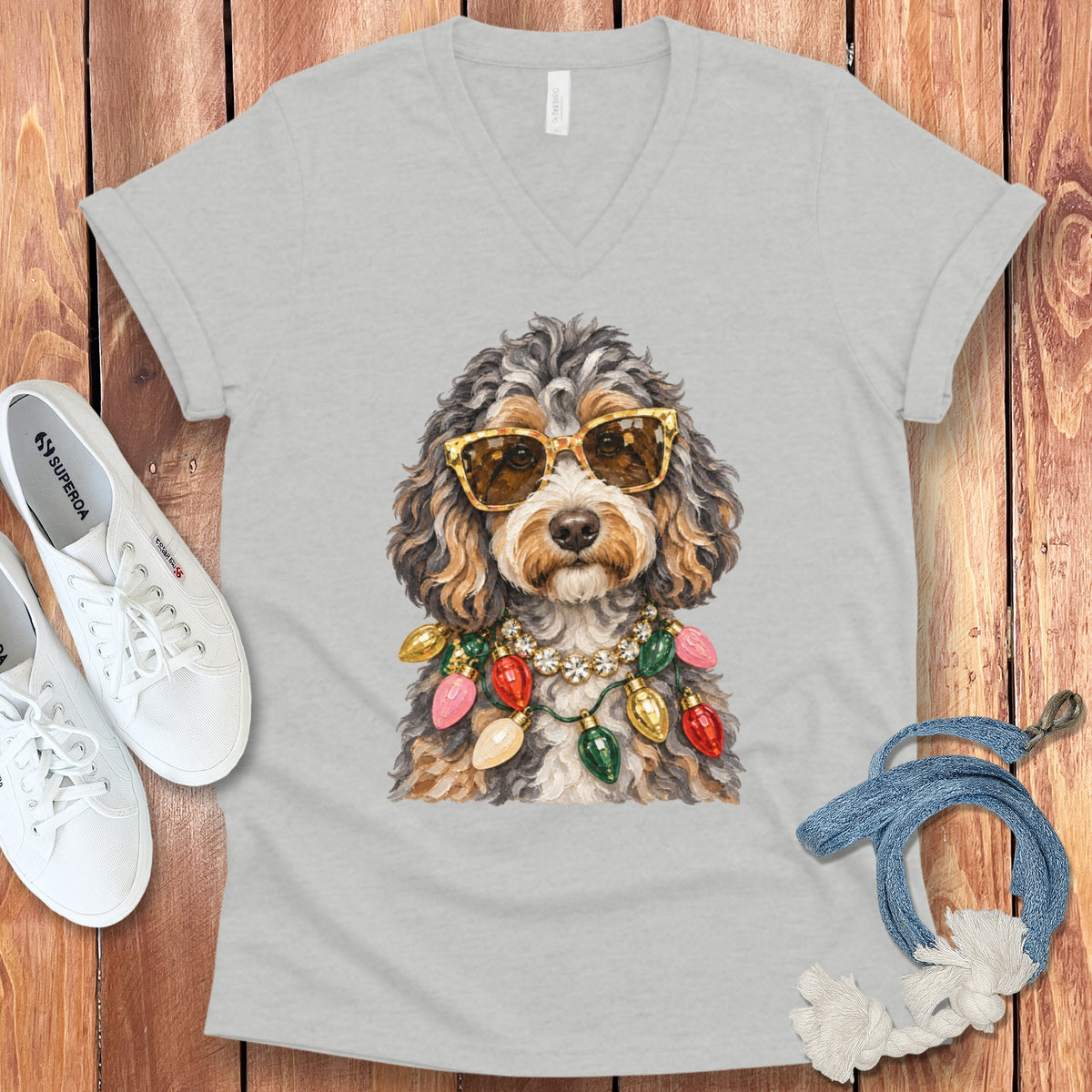Dog wearing sunglasses and a Christmas light necklace on a t-shirt.