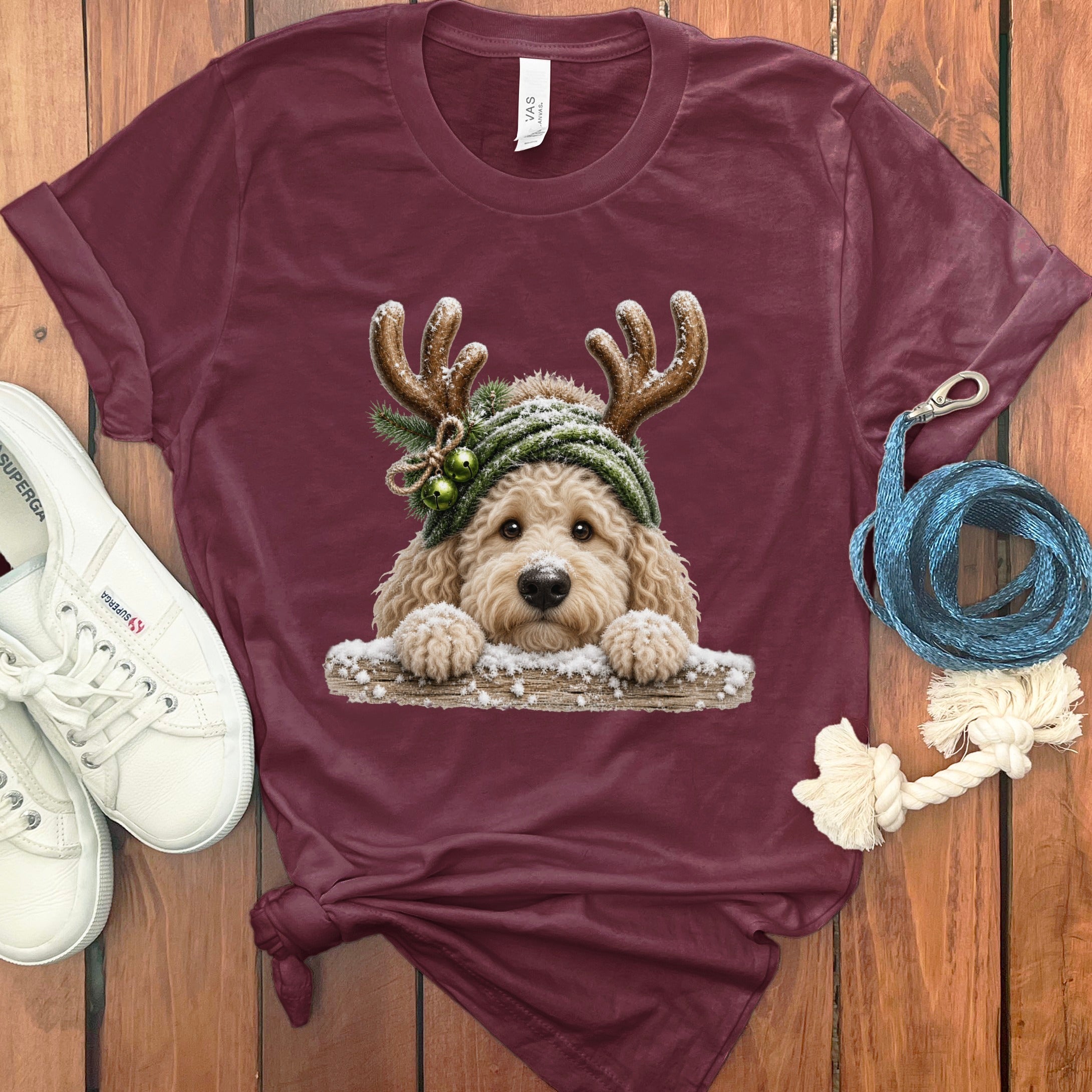 Maroon t-shirt with a doodle wearing reindeer antlers and a green beanie.