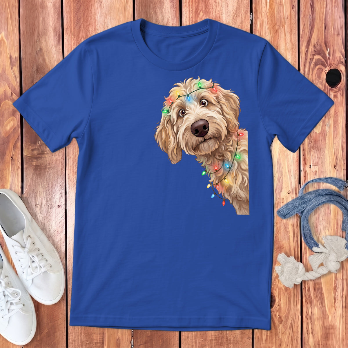Blue t-shirt with a goldendoodle peeking over a string of colorful Christmas lights.