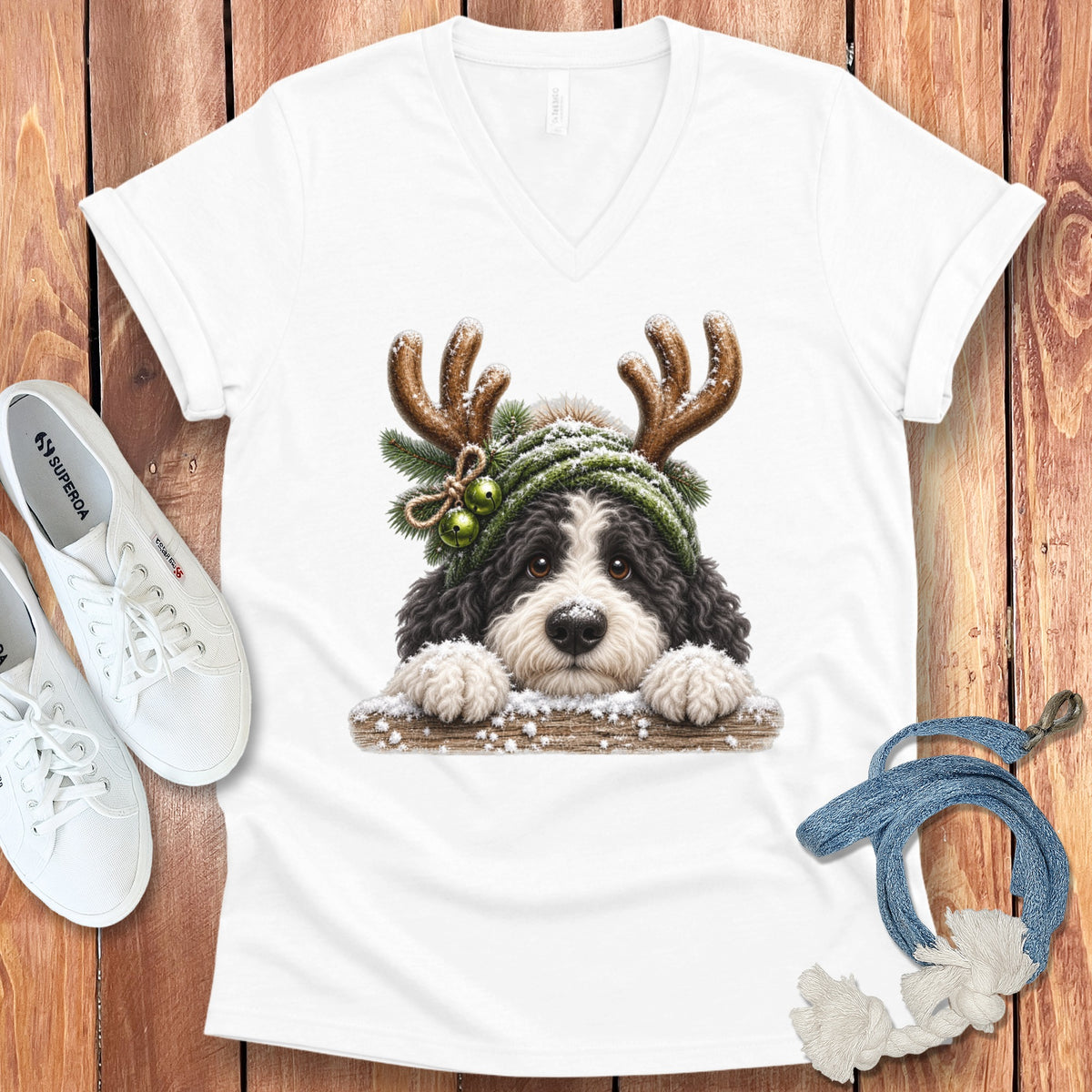 Bernedoodle puppy wearing a green beanie with antlers and jingle bells.