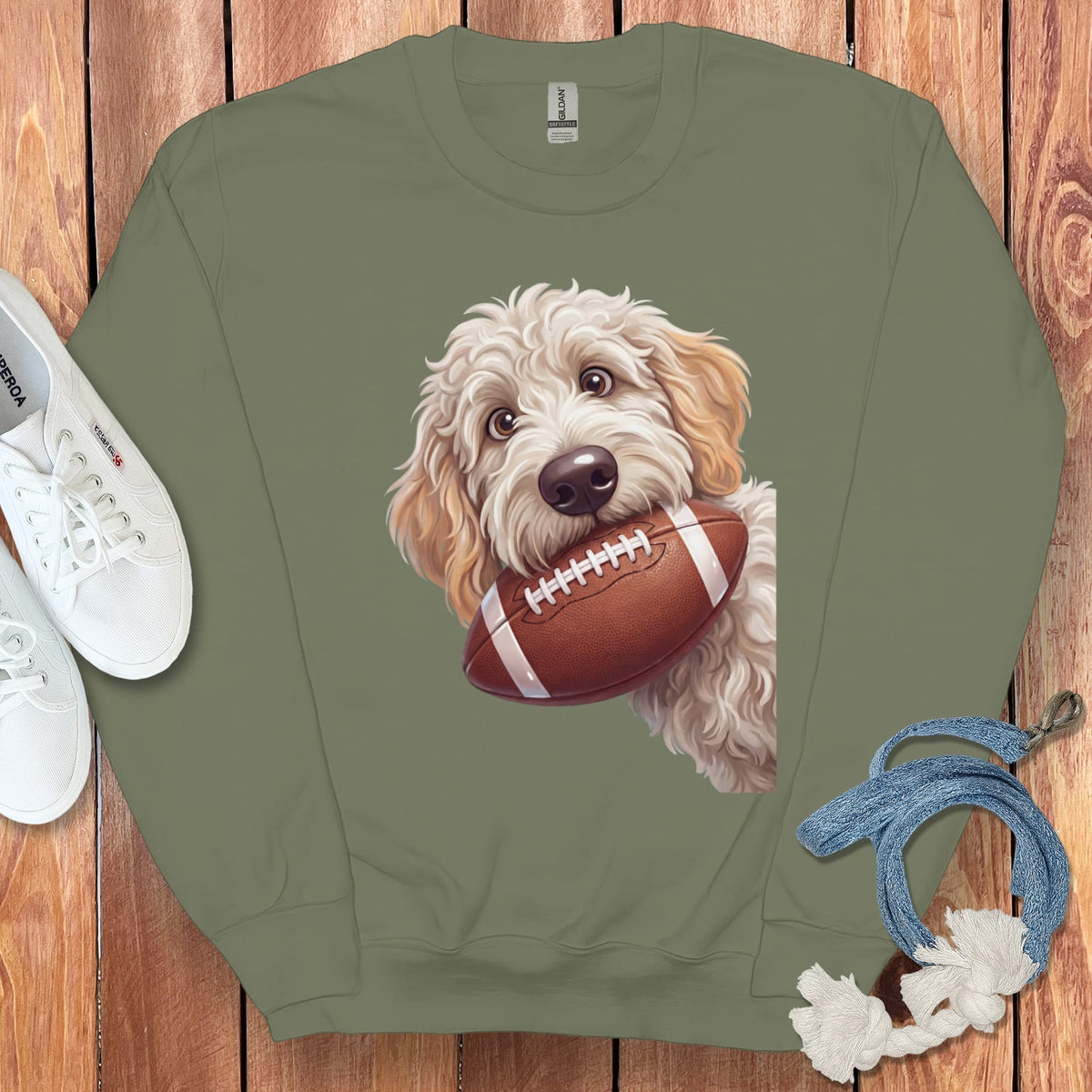 Light brown doodle dog with football on olive green crewneck sweatshirt.