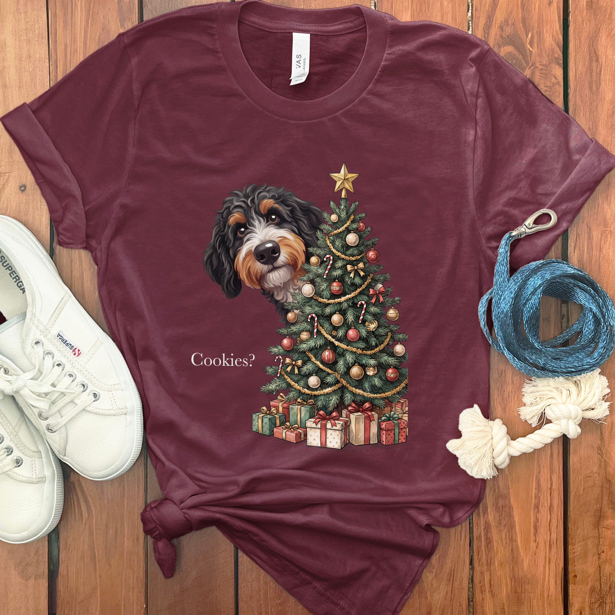 Maroon t-shirt with a dog peeking around a Christmas tree with presents and the text "Cookies?".
