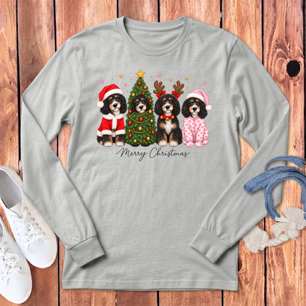 Light gray long-sleeve t-shirt with a graphic of four Bernedoodles in Christmas attire beside a decorated tree.