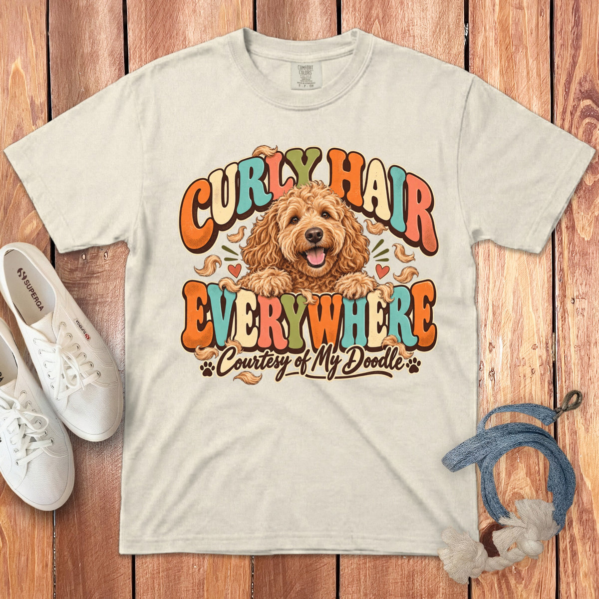 Cream t-shirt with a doodle dog and retro text saying "Curly Hair Everywhere".