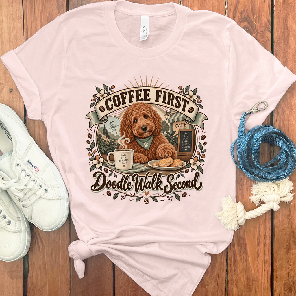 Light pink t-shirt with a doodle graphic that says "Coffee First, Doodle Walk Second".