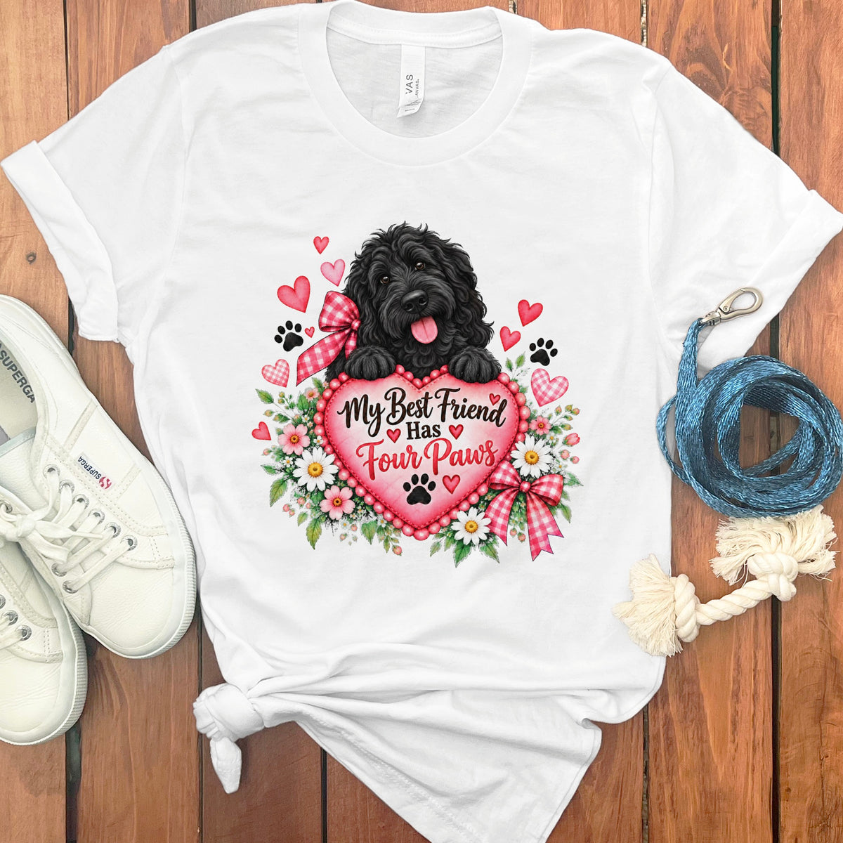 A white t-shirt featuring a graphic of a black dog holding a pink heart with flowers.