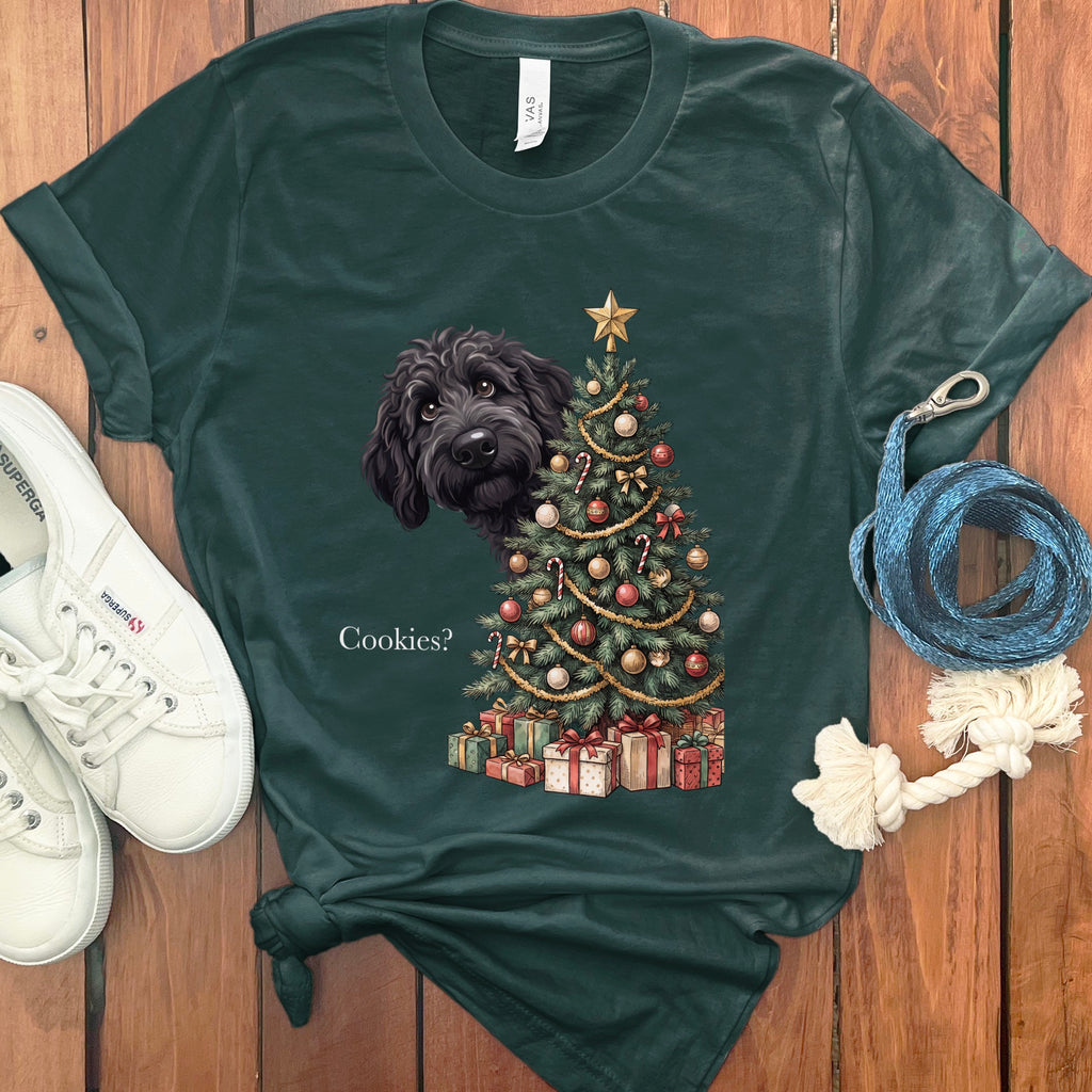 Dark green t-shirt with a black dog peeking from behind a Christmas tree with gifts.