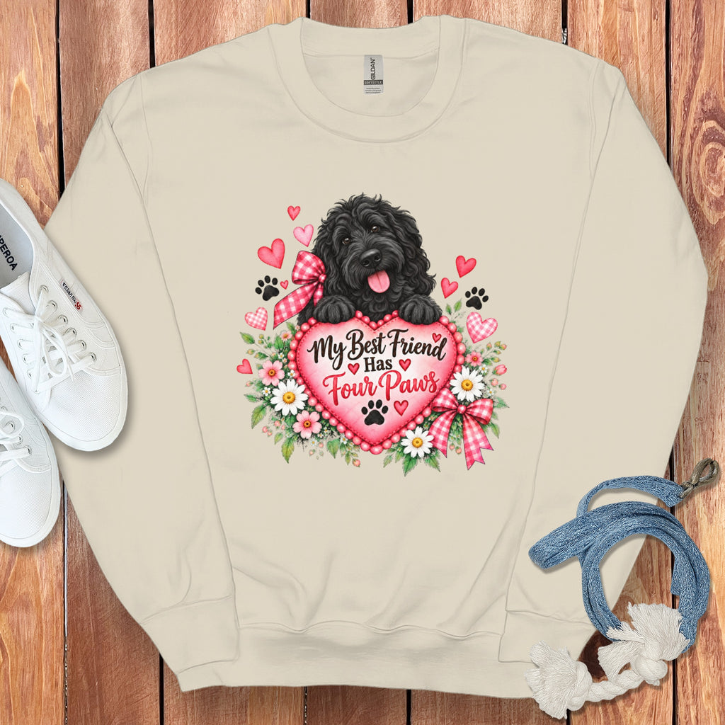 Cream-colored crewneck sweatshirt featuring a black fluffy dog resting on a pink heart with the text My Best Friend Has Four Paws surrounded by flowers and paw prints.