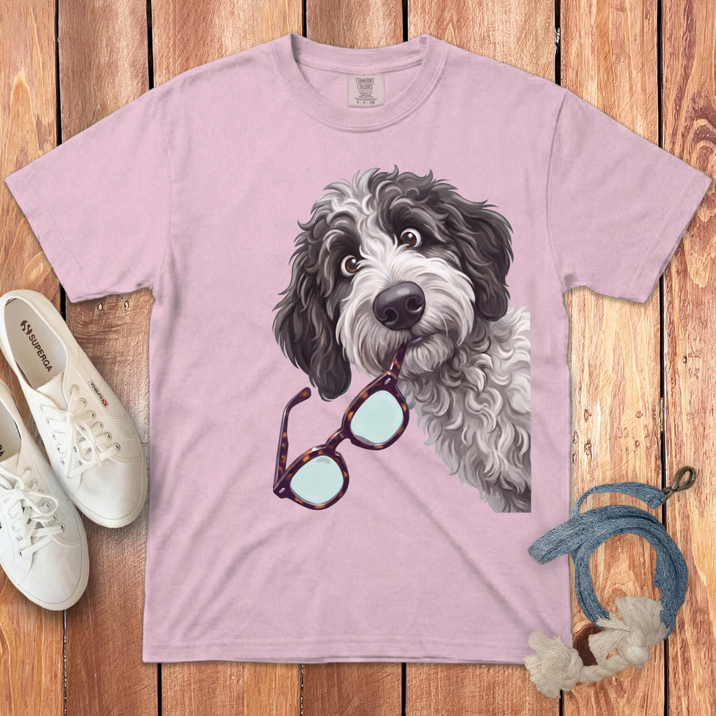 A pink t-shirt features a graphic of a shaggy black and white dog holding glasses in its mouth.