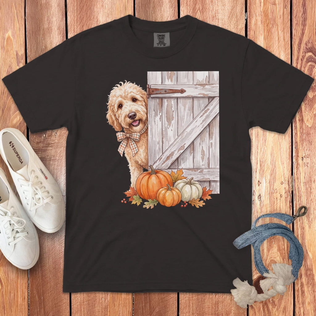Dark t-shirt featuring a golden doodle dog peeking behind a barn door with pumpkins.