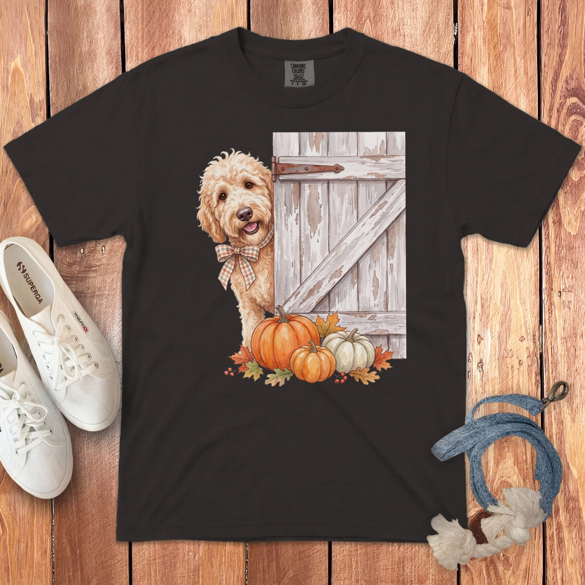 Dark t-shirt featuring a golden doodle dog peeking behind a barn door with pumpkins.