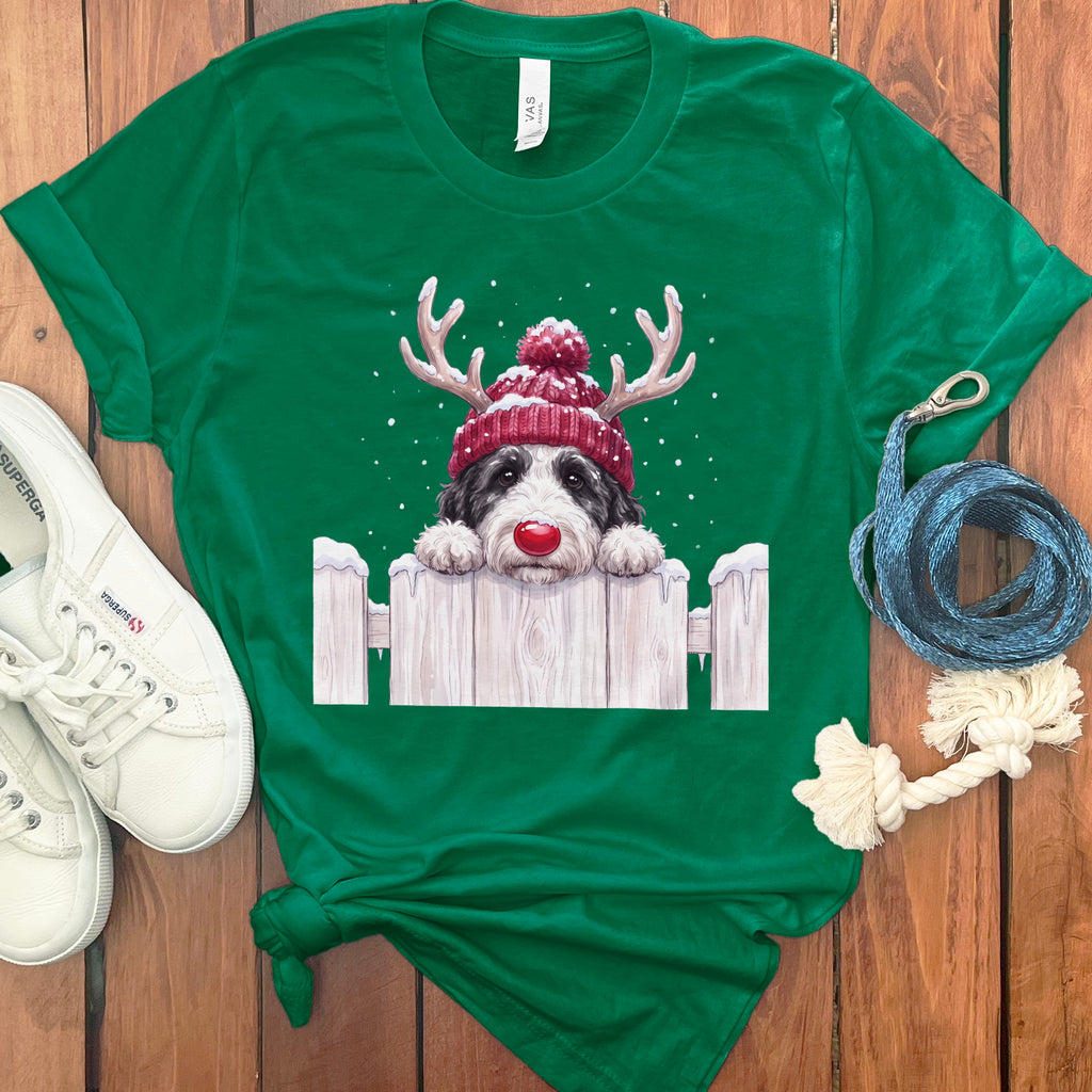 Dog with reindeer antlers and red nose peeking over white fence