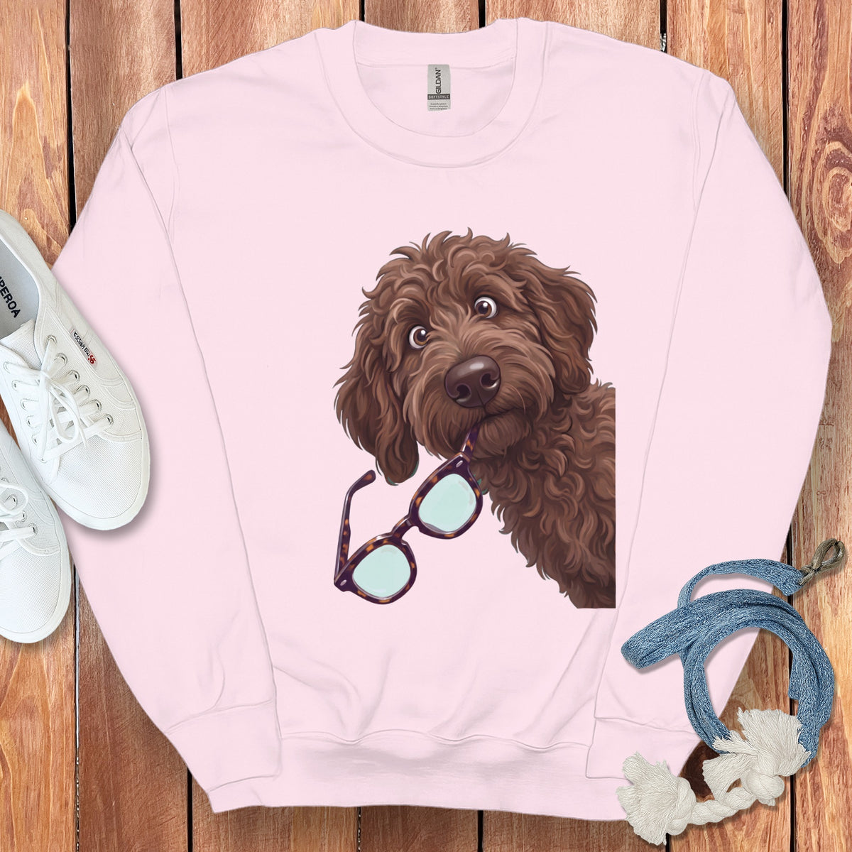 Light pink crewneck sweatshirt featuring a graphic of a brown doodle dog biting glasses.
