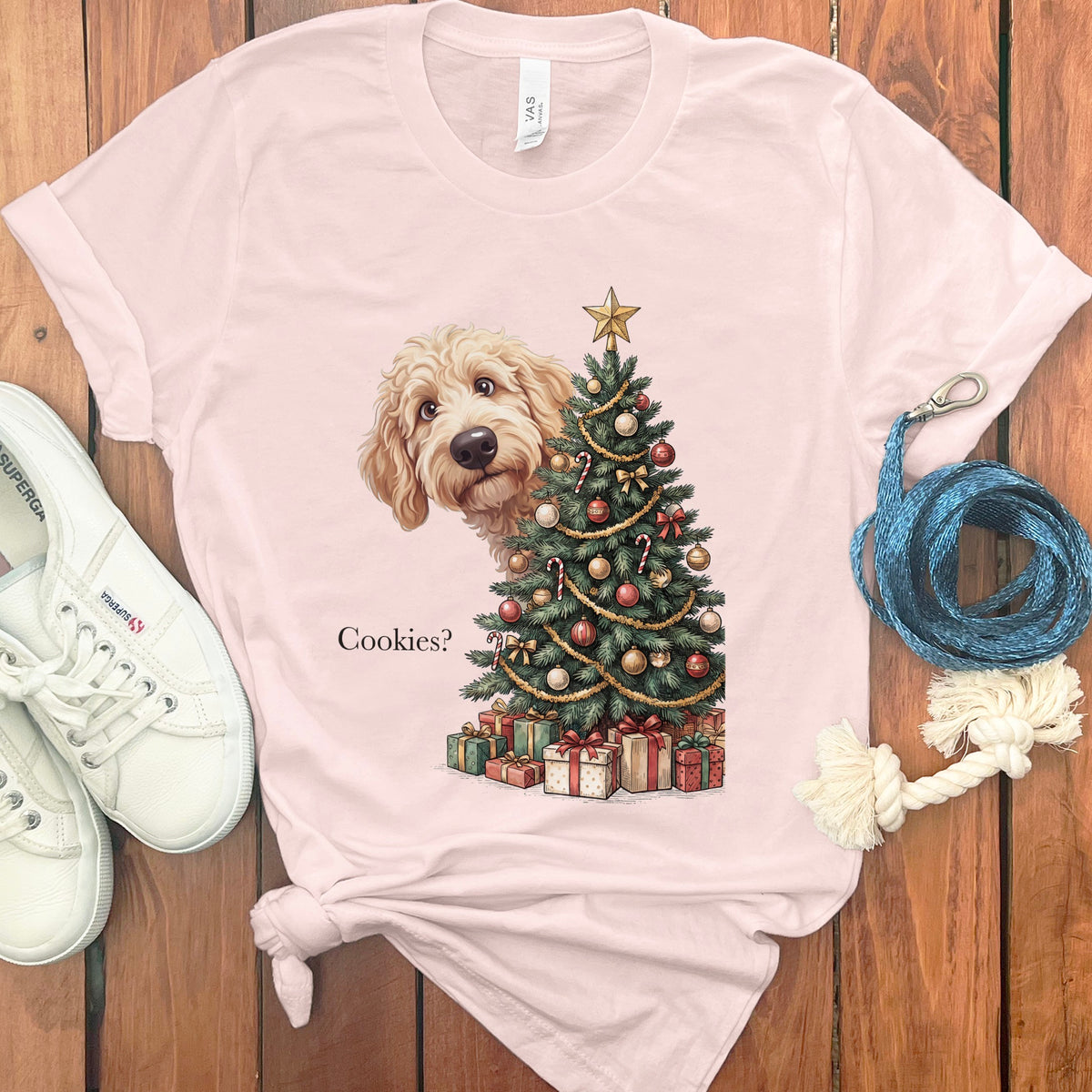 Light pink t-shirt with dog peeking behind Christmas tree and presents, text reads "Cookies?".