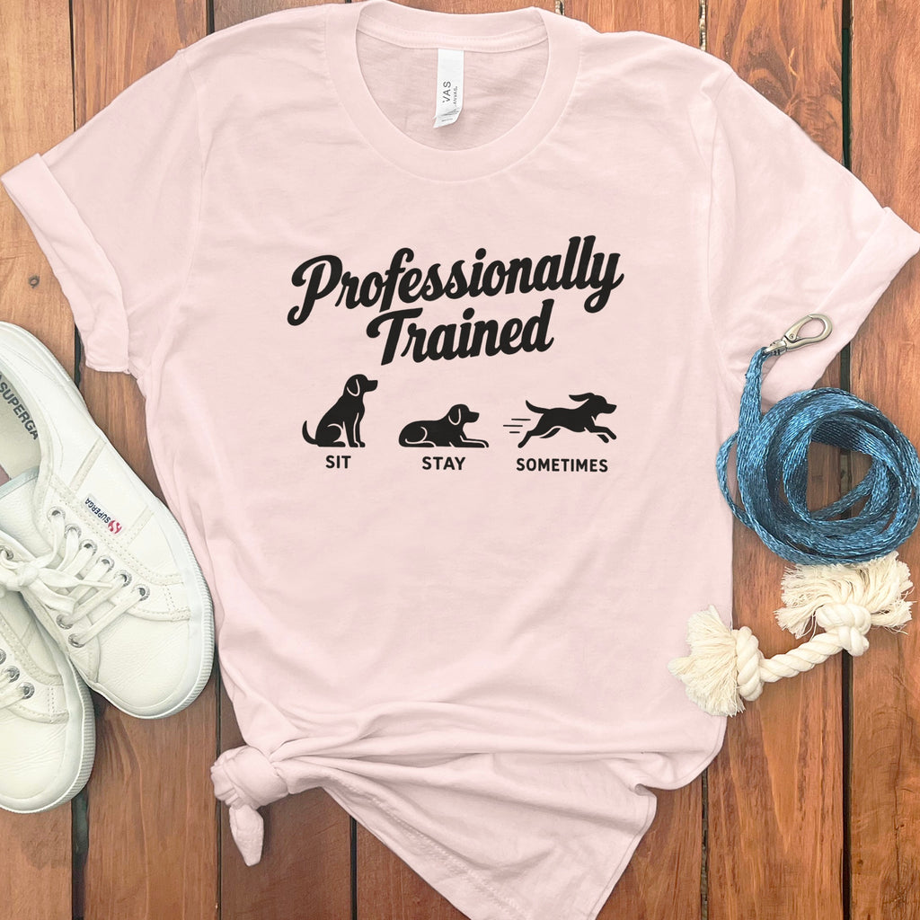 Light pink t-shirt with "Professionally Trained Sit Stay Sometimes" and dog graphics.