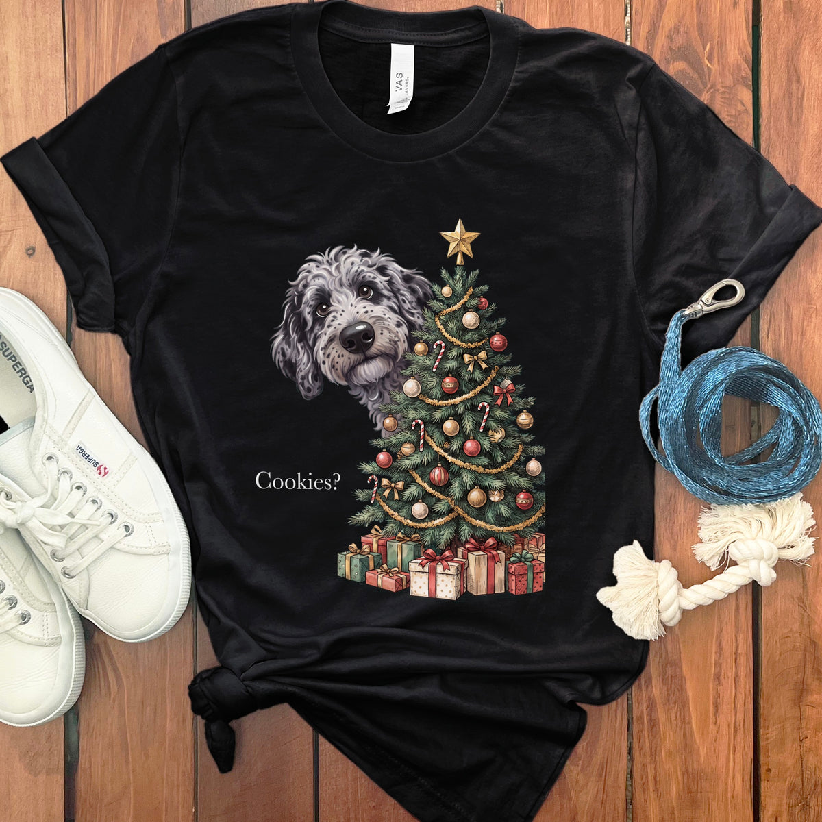 Black t-shirt with a dog peeking from behind a decorated Christmas tree and presents.