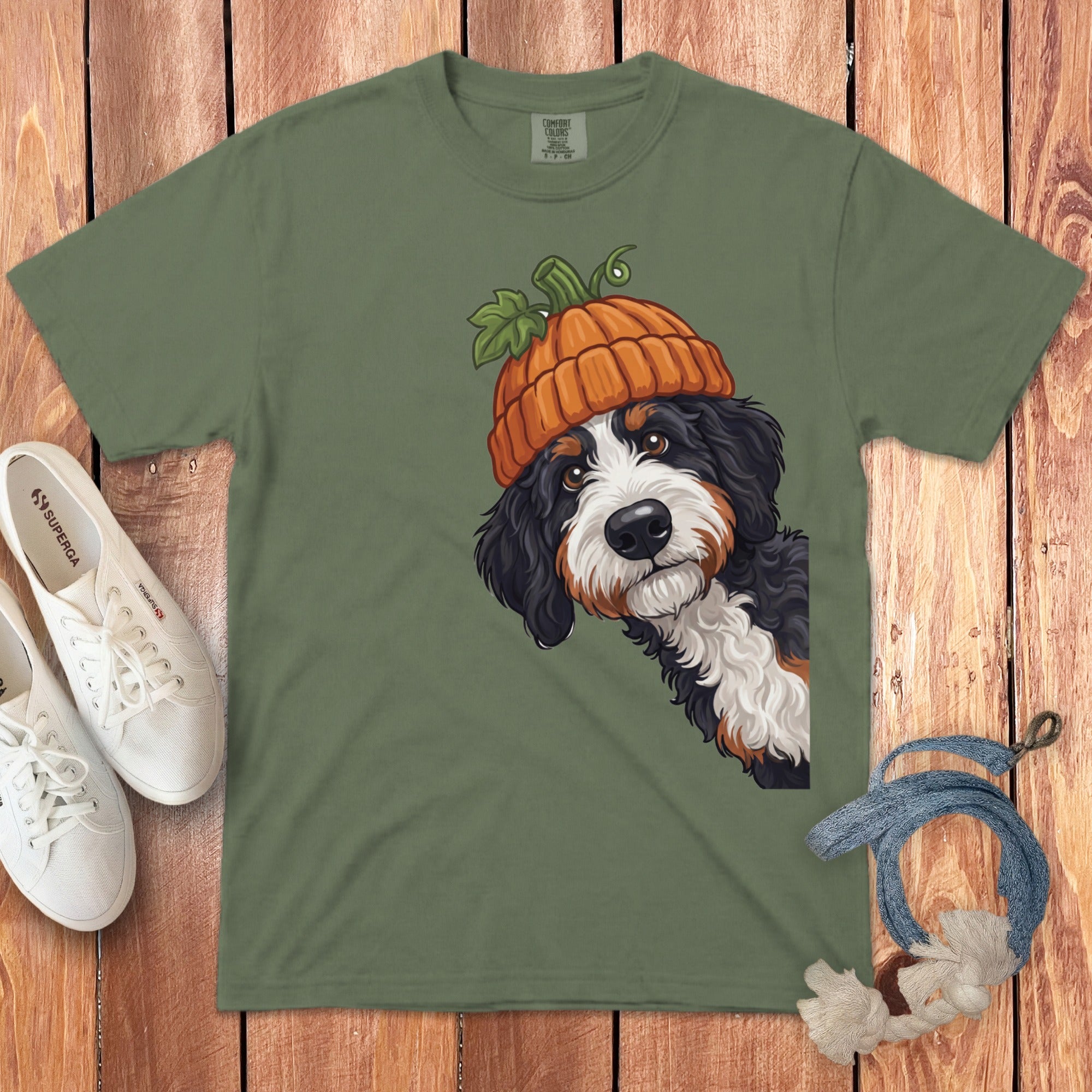 Bernese Mountain Dog wearing a pumpkin hat on a green t-shirt.