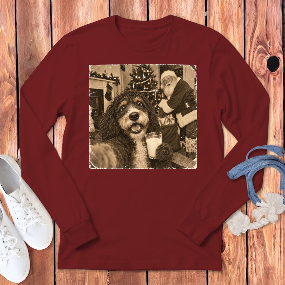 A maroon long-sleeve t-shirt with a vintage graphic showing a doodle dog holding a glass of milk with Santa Claus in the background.