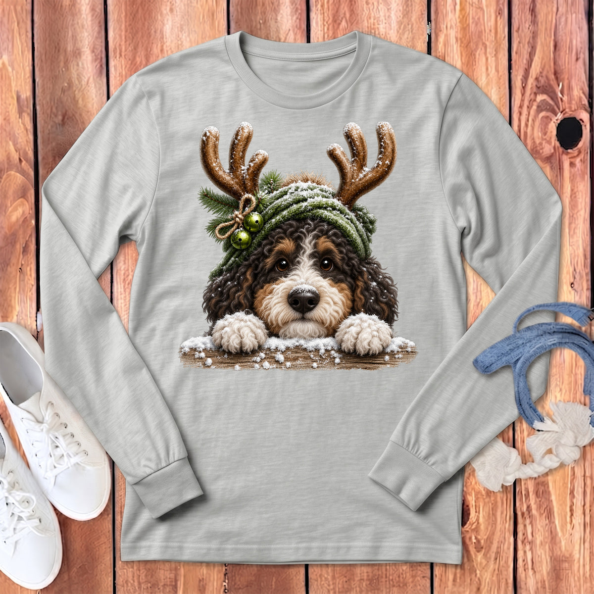 Bernedoodle dog wearing antlers and a Santa hat with festive accents on a long-sleeve shirt.