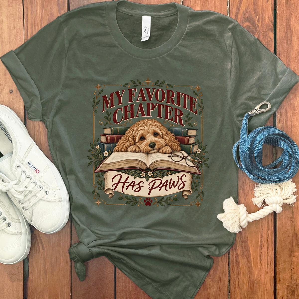 Olive green t-shirt with dog, books, glasses, and text "My Favorite Chapter Has Paws".