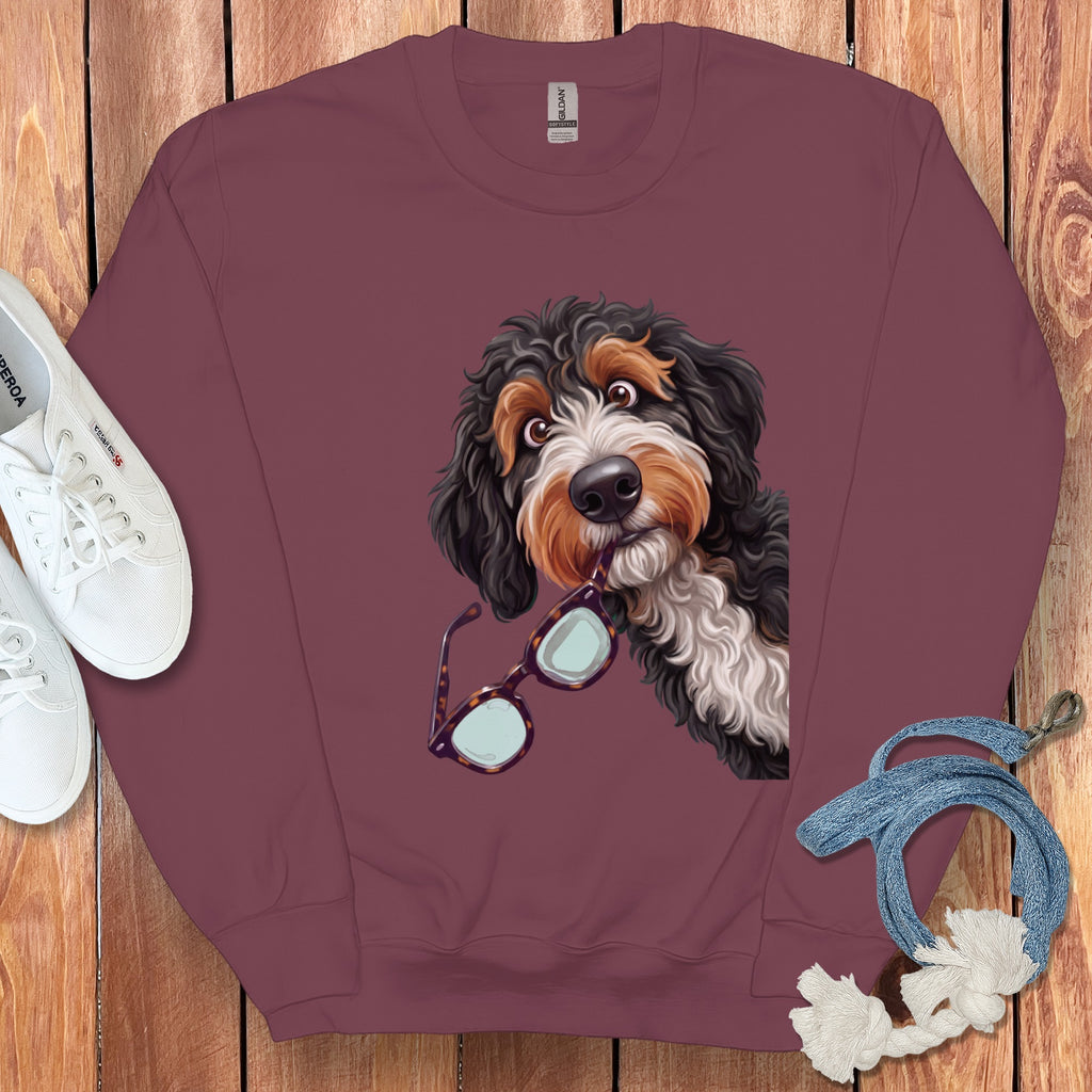 Maroon crewneck sweatshirt featuring a graphic of a Bernedoodle dog holding tortoiseshell glasses in its mouth.