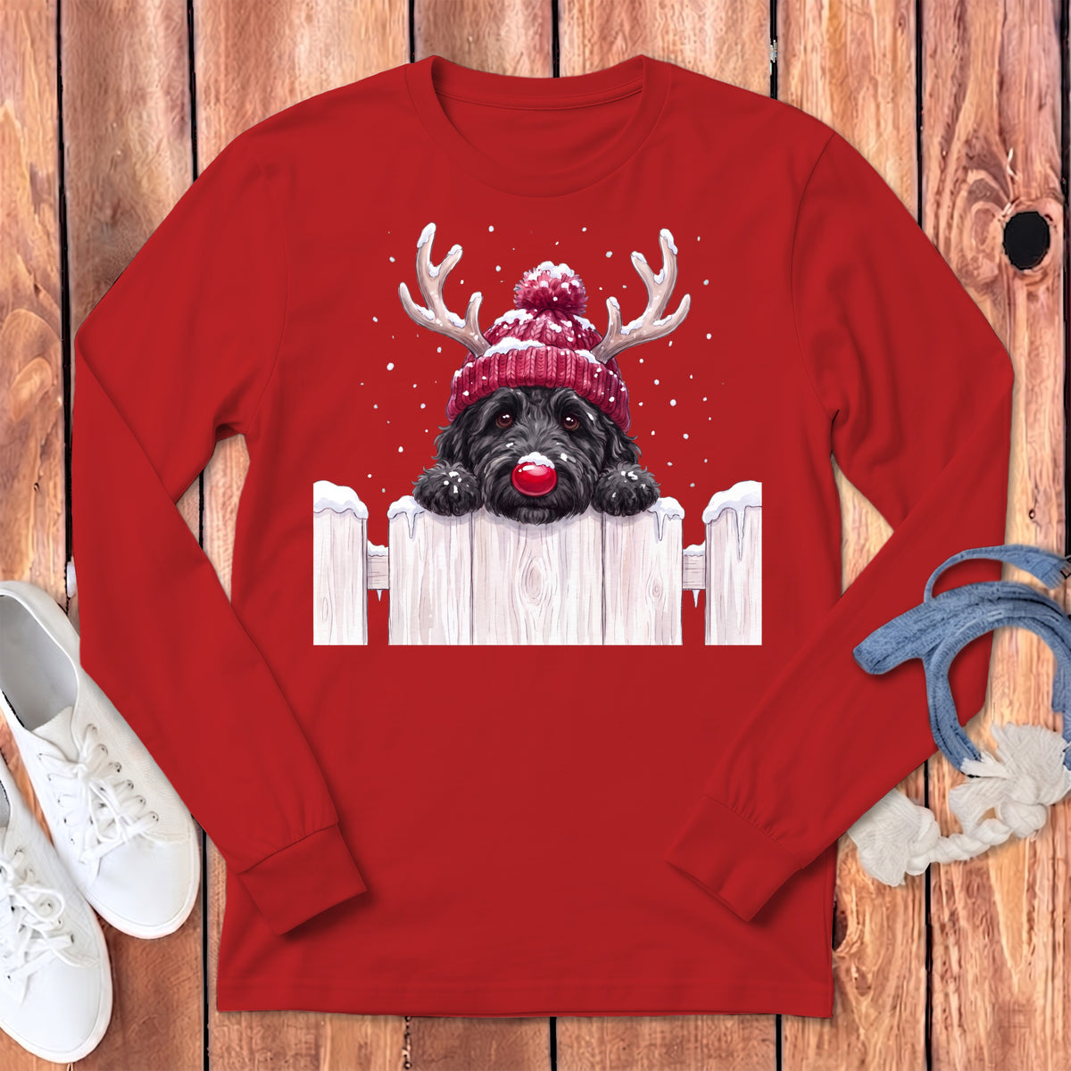 Black dog wearing a red reindeer hat with antlers and a red nose.