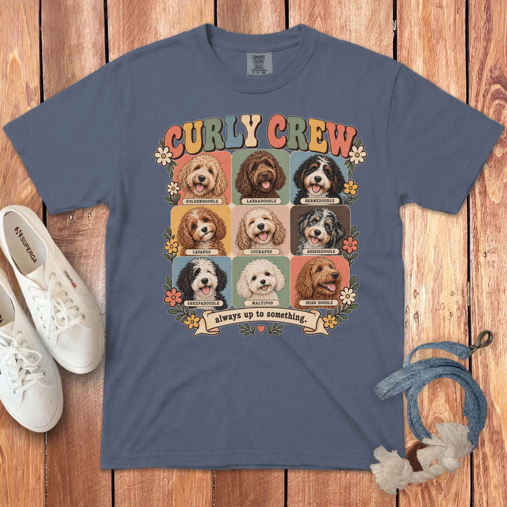A blue t-shirt displays a graphic of nine doodle dog breeds, labeled Curly Crew and always up to something.