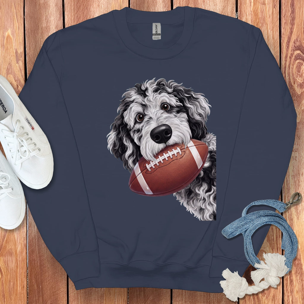 Navy sweatshirt with a doodle dog holding a football, placed on a wooden background.