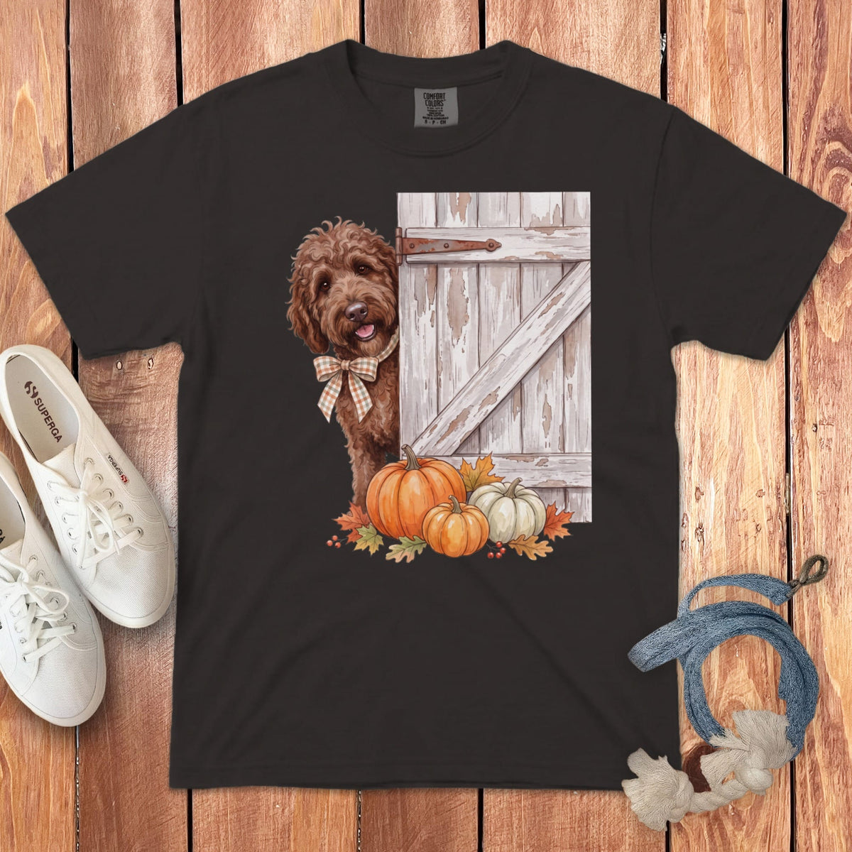 Brown doodle dog peeking from behind a rustic barn door with pumpkins and fall leaves.