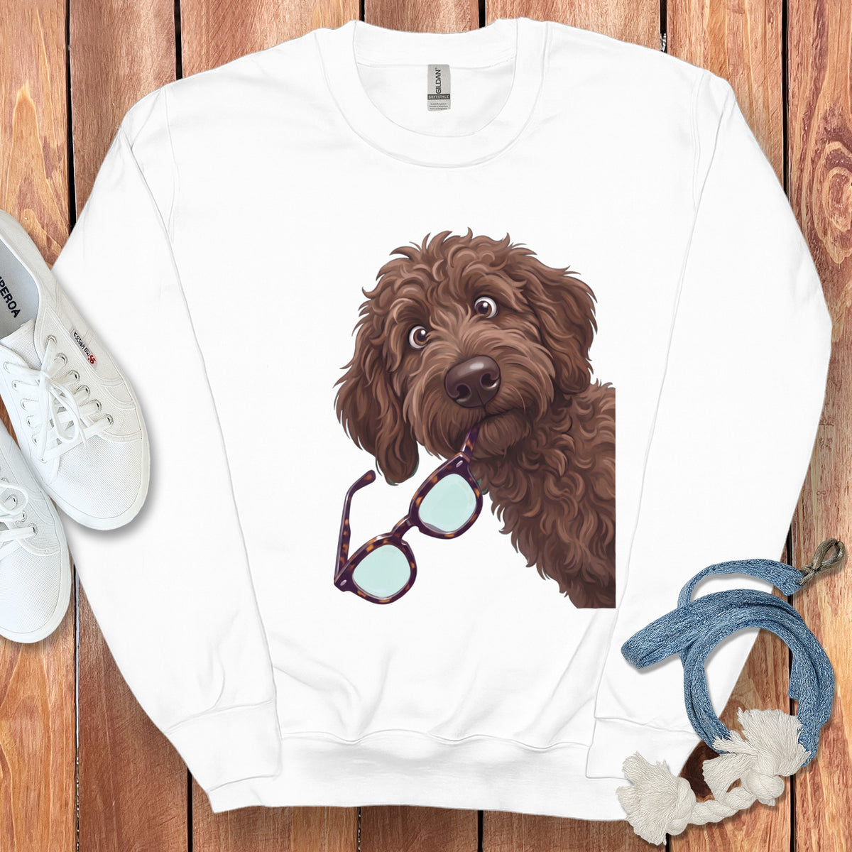 A white crewneck sweatshirt featuring a cartoon illustration of a brown fluffy dog holding glasses in its mouth.