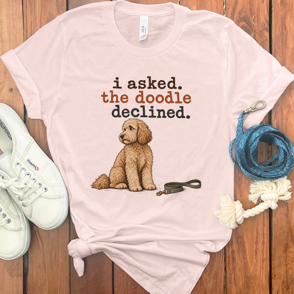 Pink t-shirt with brown text "i asked. the doodle declined." and a doodle dog illustration.