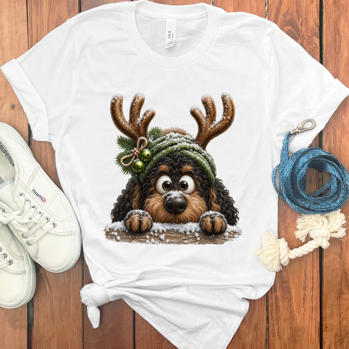 White t-shirt with cartoon dog wearing antlers and a green beanie with bells.