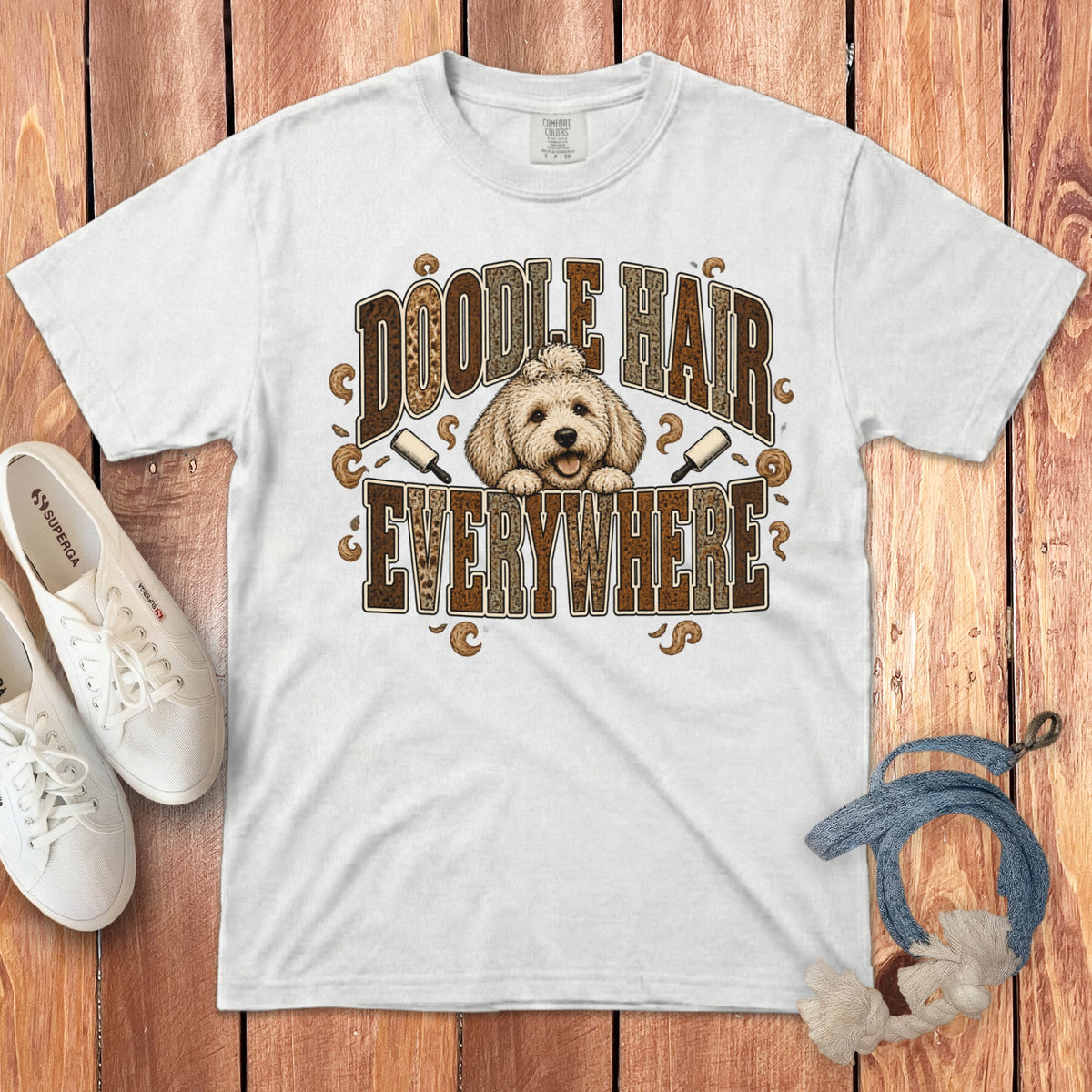 White crewneck t-shirt featuring a graphic of a Goldendoodle and the text Doodle Hair Everywhere on a wooden background.